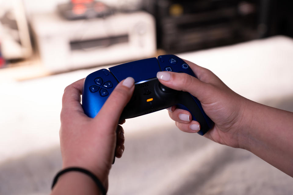 A person is holding a Sony DualSense wireless gaming controller in galactic purple. (Photo by Nikos Pekiaridis/NurPhoto via Getty Images)