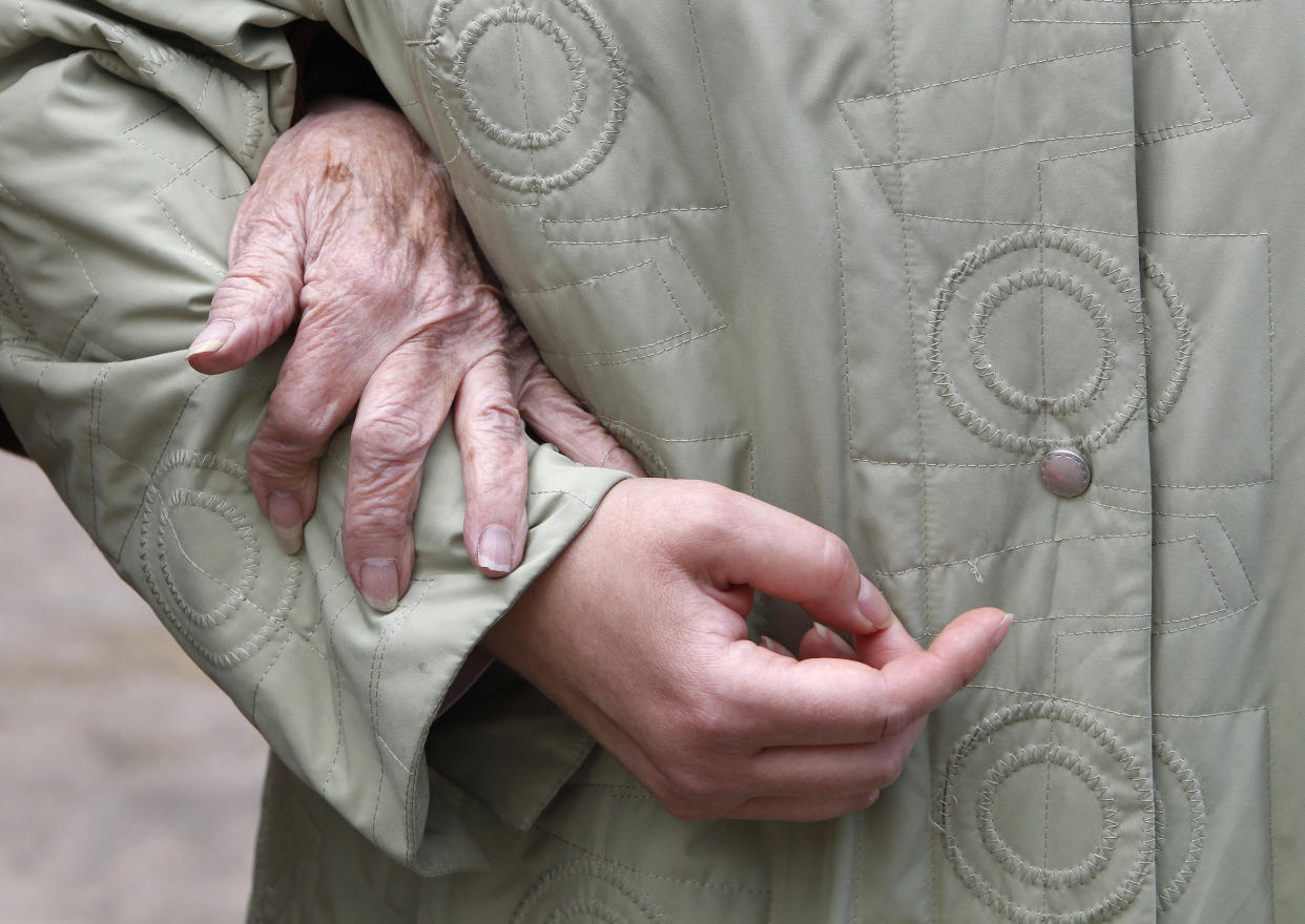 An elderly woman is escorted by an aide in London, March 22, 2010. REUTERS/Suzanne Plunkett     (BRITAIN - Tags: SOCIETY HEALTH)