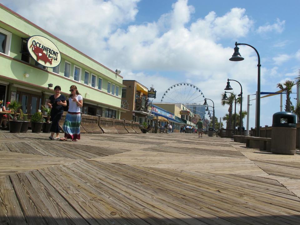 This May 22, 2013 photo shows vacationers along the boardwalk in Myrtle Beach, S.C. It is just over a mile (1.6 kilometers) and was completed three years ago at a cost of more than $6 million. May John Rhodes has said he would like the city to eventually build the worlds longest boardwalk, one running 4.6 miles along the shore. (AP Photo/Bruce Smith)