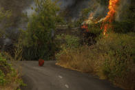 A molten rock from volcano lava sits in the middle of a road near El Paso on the island of La Palma in the Canaries, Spain, Monday, Sept. 20, 2021. Giant rivers of lava are tumbling slowly but relentlessly toward the sea after a volcano, seen in the backround, erupted on a Spanish island off northwest Africa. The lava is destroying everything in its path but prompt evacuations helped avoid casualties after Sunday's eruption. (Kike Rincon, Europa Press via AP)