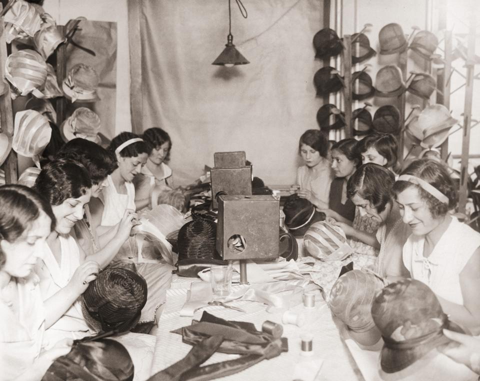 A group of young women sewing hats at a factory.