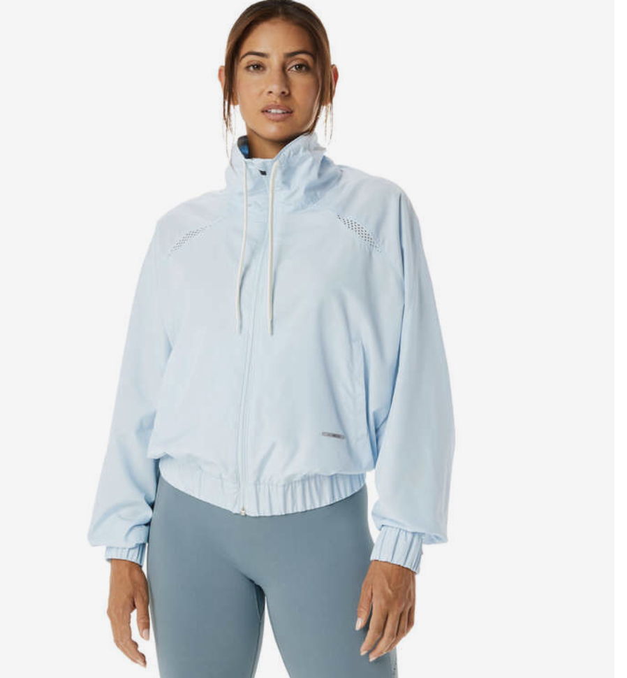 A woman stands in the Asics Womens Nagino Actibreeze Woven Jacket