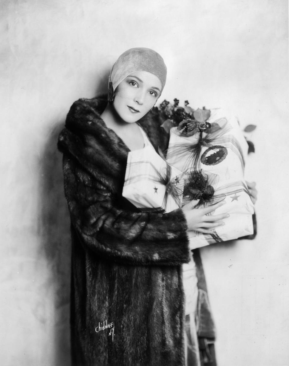 <p>Dolores Del Río fought of the winter chill in a long fur coat in 1925. The Mexican film star topped the look off with a head cap and a handful of beautifully wrapped Christmas presents.</p>