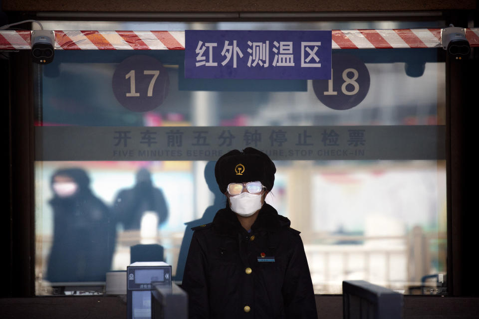 A station worker wears a face mask and goggles as she waits to check passengers' tickets at the Beijing Railway Station in Beijing, Saturday, Feb. 15, 2020. People returning to Beijing will now have to isolate themselves either at home or in a concentrated area for medical observation, said a notice from the Chinese capital's prevention and control work group published by state media late Friday. (AP Photo/Mark Schiefelbein)