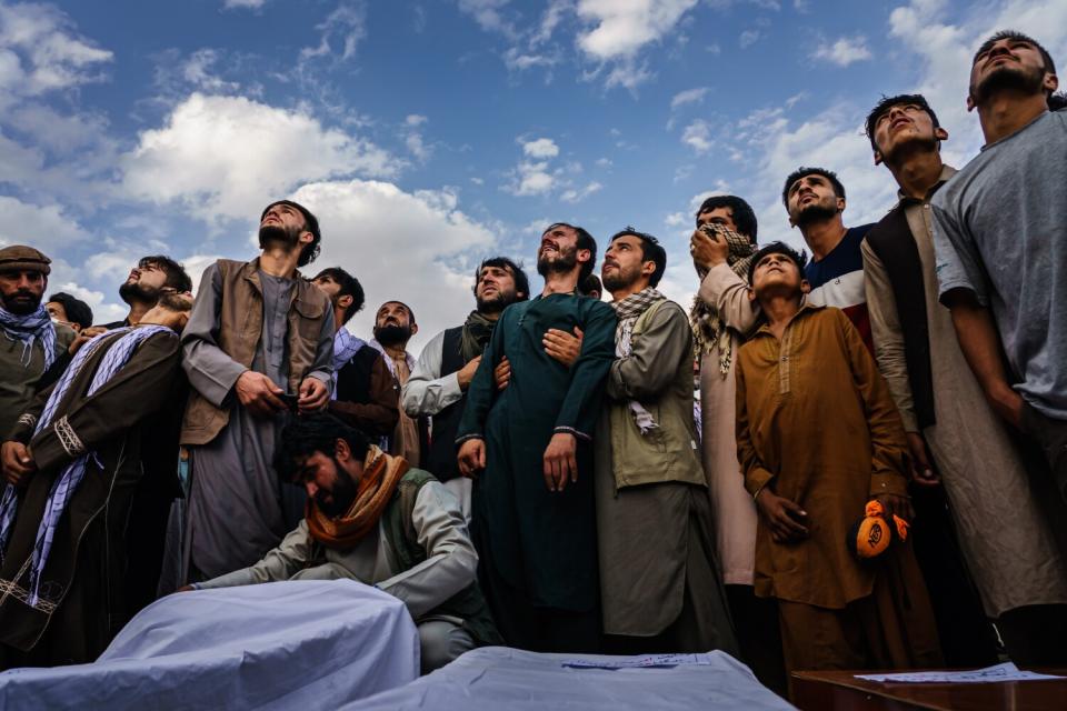 A crowd of men look at the sky.