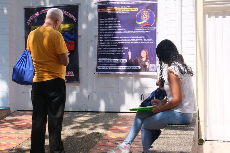 Posters hanging on the side of the new Venezuelan consulate in Medellin, Colombia list the services offered inside, including the issuing of marriage certificates and passports. People stopped to take photos on Tuesday. Photo by Austin Landis/UPI