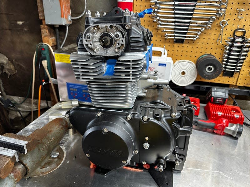 A modified Honda CB350 twin engine sits on a workbench