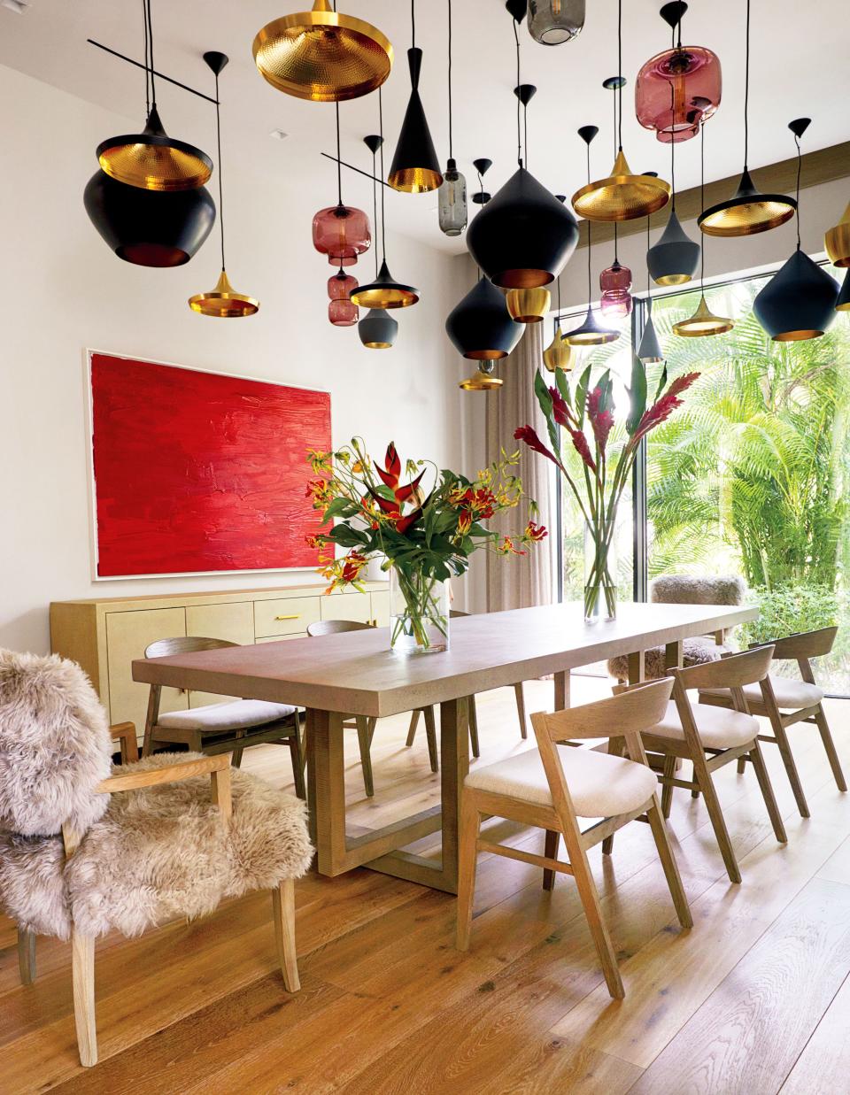 A grouping of pendant lamps by Tom Dixon (brass) and Simon Legald for Normann Copenhagen (Glass) sets the tone in the dining room. Artwork by Serena Williams.