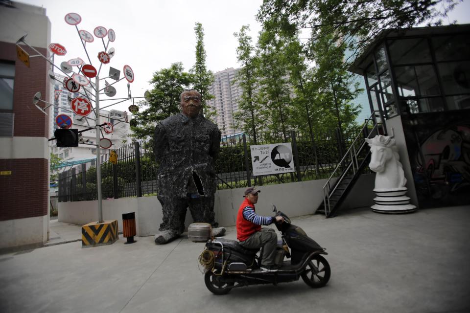 In this May 8, 2013 photo, a man rides a scooter near the artistic objects at the Moganshan Road Art District in Shanghai, China. The city’s most prominent contemporary galleries _ locals as well as outposts of European and U.S. galleries _ are housed in converted textile factories and warehouses dating to the 1930s. Moganshan’s mix of industrial and arty is a favorite backdrop for Chinese fashion photographers. (AP Photo/Eugene Hoshiko)