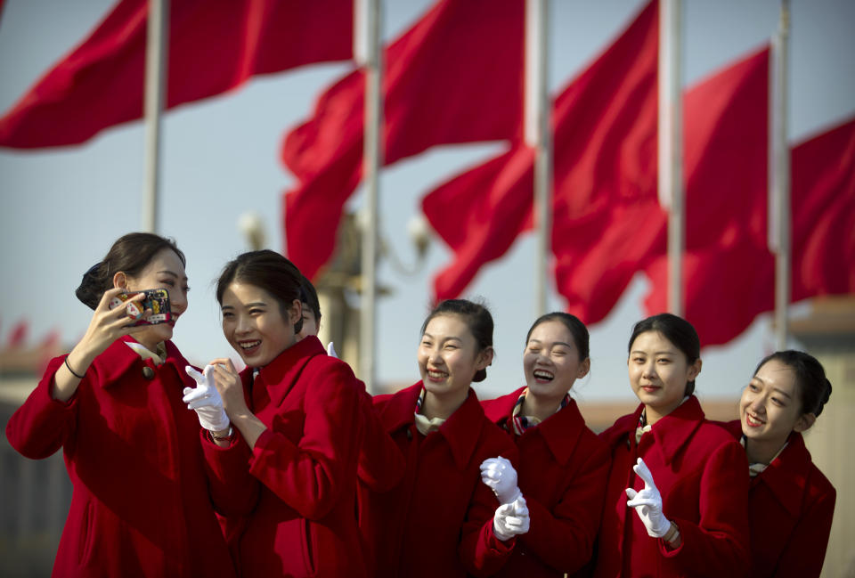 Bus ushers react as they pose for a selfie during a meeting one day ahead of the opening session of China's National People's Congress (NPC) at the Great Hall of the People in Beijing, Monday, March 4, 2019. A year since removing any legal barrier to remaining China's leader for life, Xi Jinping appears firmly in charge, despite a slowing economy, an ongoing trade war with the U.S. and rumbles of discontent over his concentration of power. (AP Photo/Mark Schiefelbein)