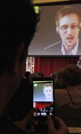 A supporter of Amnesty International shoots a mobile phone video as accused government whistleblower Edward Snowden speaks via teleconference during the Amnesty International Human Rights Conference 2014 in Chicago, April 5, 2014. REUTERS/Frank Polich