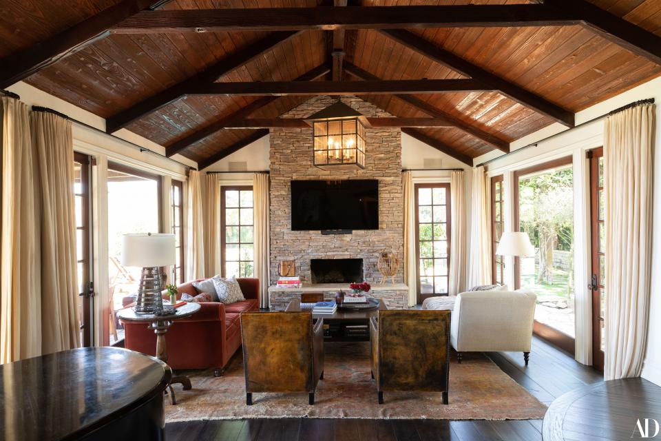 The grand windows and the stone hearth—not to mention the slanted and timbered ceilings (which feature a lantern from Paul Ferrante)—define the main room. The furniture is custom and differently textured, from the fabric chaise and couch (from Chris Barrett Design) to the leather chairs (from Brenda Antin).