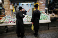 Ultra-Orthodox Jewish men speak to a vendor at a fruit and vegetable stall in a market in Jerusalem May 11, 2017. Picture taken May 11, 2017. REUTERS/Amir Cohen