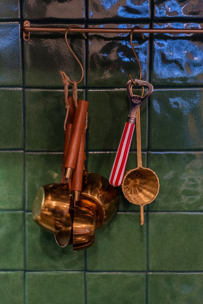 Kitchen utensils against a green backsplash.