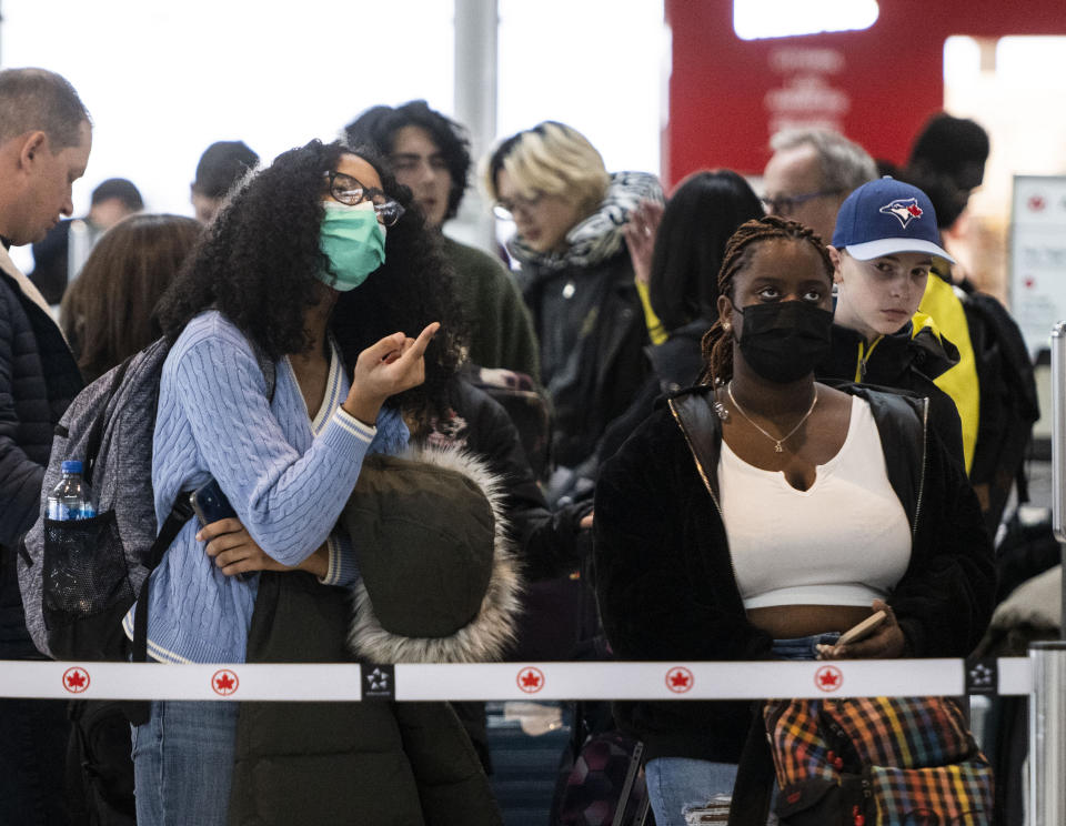 Travelers look at a screen showing departures at the Ottawa International Airport, as airlines cancel or delay flights during a major storm in Ottawa, on Friday, Dec. 23, 2022. (Justin Tang /The Canadian Press via AP)