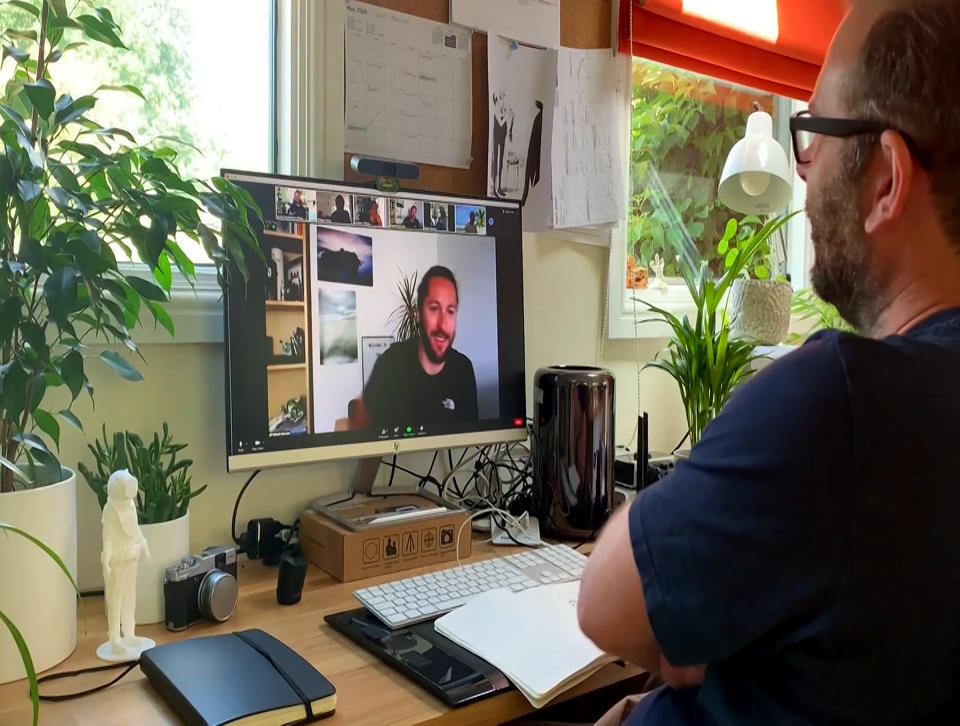 This July 2020 photo taken from video released by Locksmith Animation shows art director Justin Hutchinson-Chatburn, right, communicating on his computer during the filming of a video diary. The London animation studio Locksmith had been in production on "Ron's Gone Wrong" for more than two years before the pandemic hit. Suddenly, animators found themselves on lockdown wrestling with glitchy technology. Hutchinson-Chatburn said it’s remarkable that animation is “thriving and surviving” during the pandemic, but he’s hoping to gather with work colleagues in person soon. (Locksmith Animation via AP)