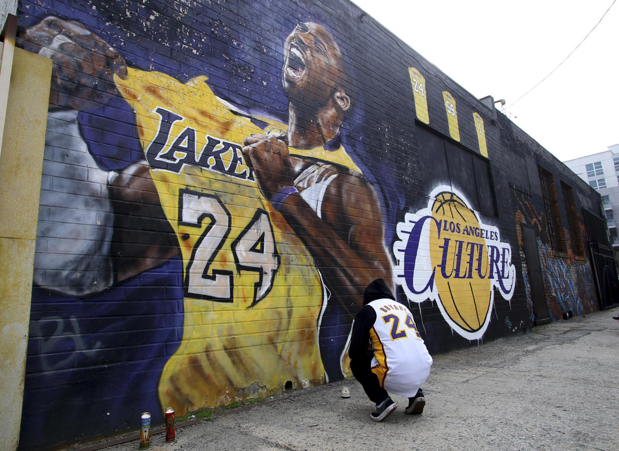 A fan pays respects at a mural depicting Kobe Bryant in a downtown Los Angeles alley after word of the Lakers star's death in a helicopter crash, in downtown Los Angeles Sunday, Jan. 26, 2020. (AP Photo/Matt Hartman)