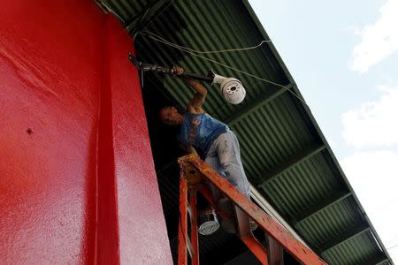 Cuban migrant Barbaro Rodriguez, 43, who run out of money, works painting a private business in Paso Canoas on the border with Costa Rica March 22, 2016. REUTERS/Carlos Jasso