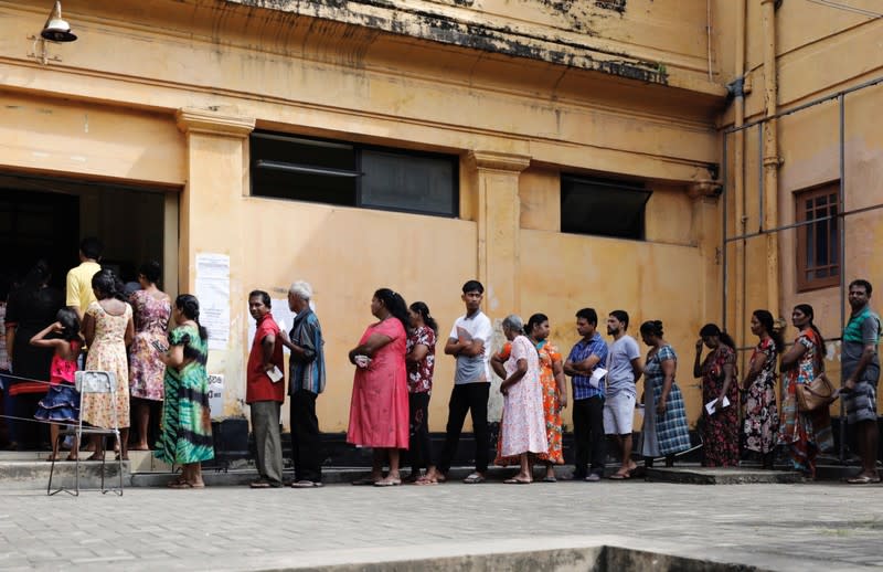 People stand in a line to cast their votes during the presidential election at polling station in Colombo