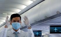 An attendant wearing a protective mask guides the flight safety procedures before take off of a Vietnam Airlines flight, following an outbreak of the novel coronavirus, at Danang airport in Danang city