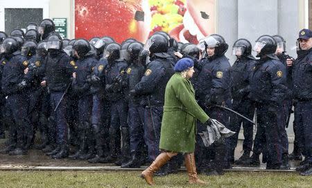 Law enforcement officers gather as a woman walks past during a rally, denouncing the new tax on those not in full-time employment and marking the 99th anniversary of the proclamation of the Belarussian People's Republic, in Minsk, Belarus, March 25, 2017. REUTERS/Vasily Fedosenko