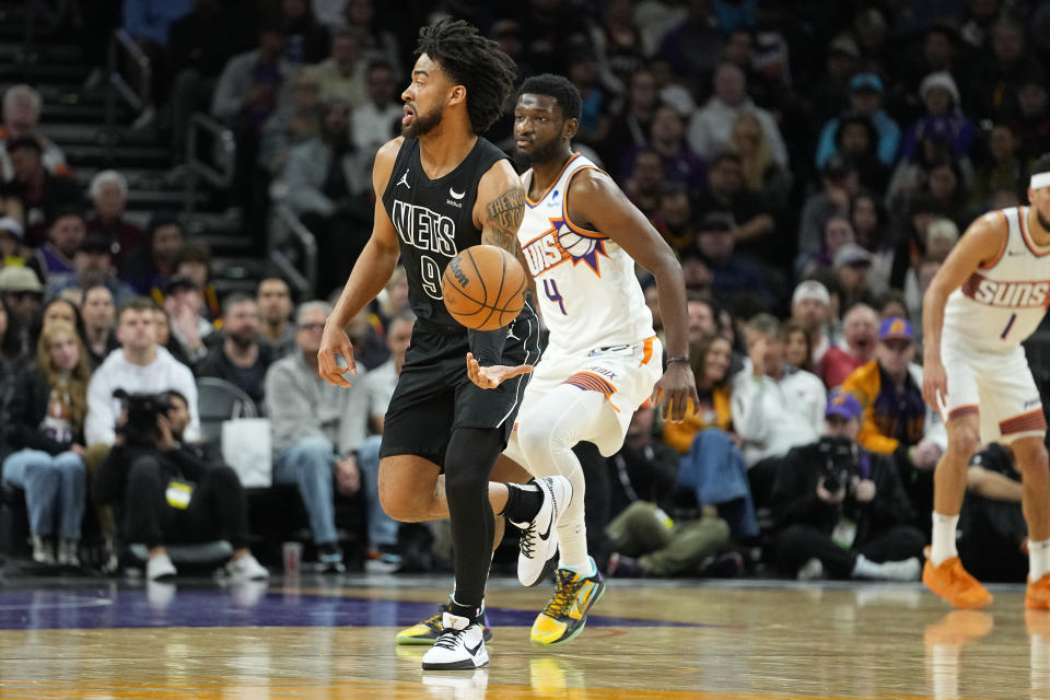 Brooklyn Nets forward Trendon Watford (9) hands off as Phoenix Suns forward Chimezie Metu (4) looks on during the first half of an NBA basketball game, Wednesday, Dec. 13, 2023, in Phoenix. (AP Photo/Matt York)