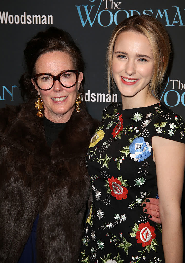 Two women posing together at an event, one in a floral dress, the other in a fur coat