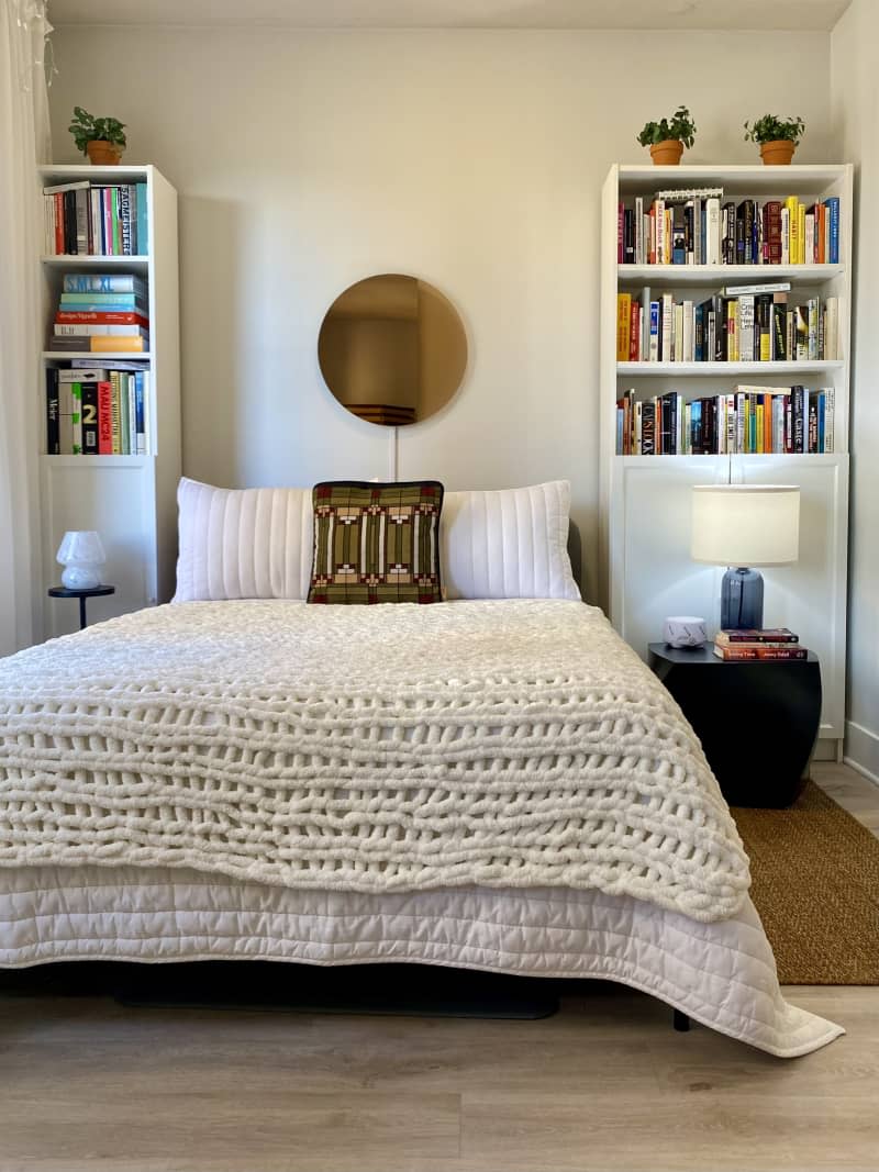 Large bed flanked by two bookshelves and nightstand with lamps.