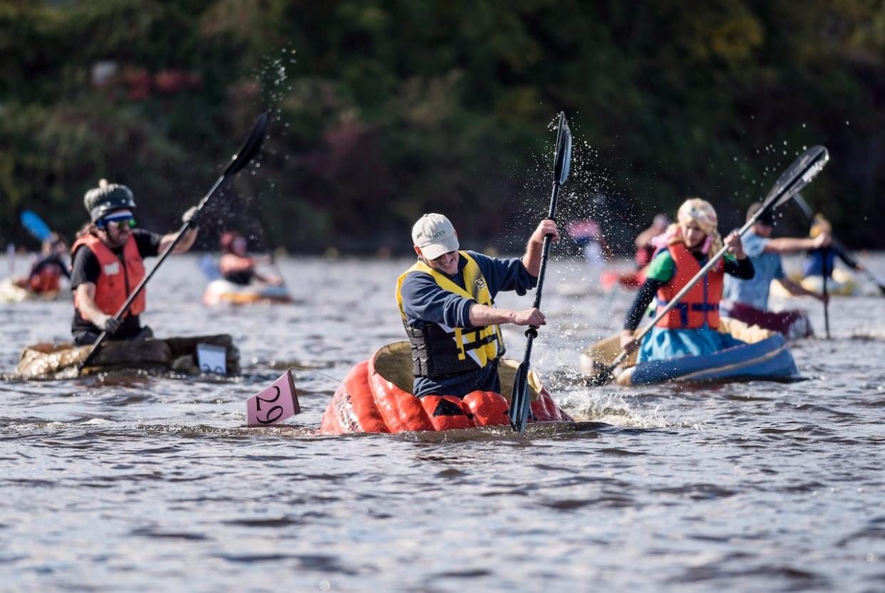 Participants in the 20th annual Windsor-West Hants Pumpkin Festival regatta paddle giant pumpkins on Lake Pisiquid in Windsor, N.S., in 2018. (Darren Calabrese/The Canadian Press - image credit)