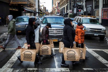 Employees carry delivery bags full of food out of a Shake Shack store in New York January 30, 2015. Shares of hamburger chain Shake Shack Inc soared as much as 150 percent in their first day of trading on Friday, valuing the company that grew out of a hotdog cart in New York's Madison Square Park at nearly $2 billion. REUTERS/Lucas Jackson (UNITED STATES - Tags: BUSINESS FOOD)