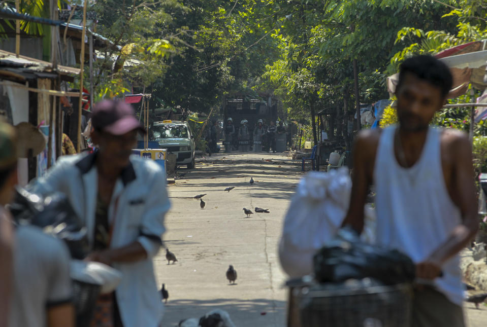 Railway workers, participants of a "civil disobedience movement" (CDM) against the military takeover of power leave their government provided houses with their belongings as riot policemen watch in Yangon, Myanmar Wednesday, March 10, 2021. Armed soldiers and riot policemen arrived in the morning and ordered the workers and their families who participate in the CDM to vacate their housing. (AP Photo)