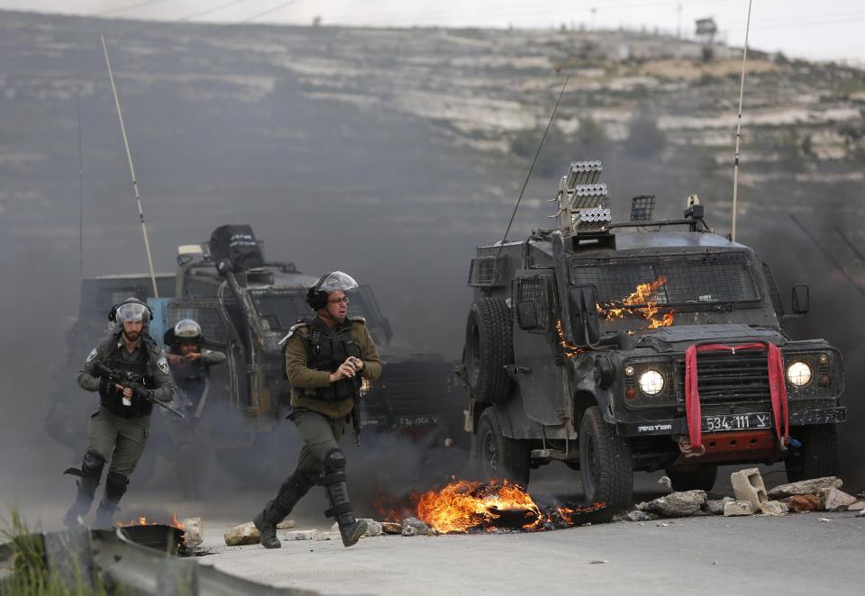 Israeli border policemen move away from a burning vehicle during clashes with Palestinians at checkpoint Bet El near the West Bank city of Ramallah , Wednesday, March 27, 2019.(AP Photo/Majdi Mohammed)