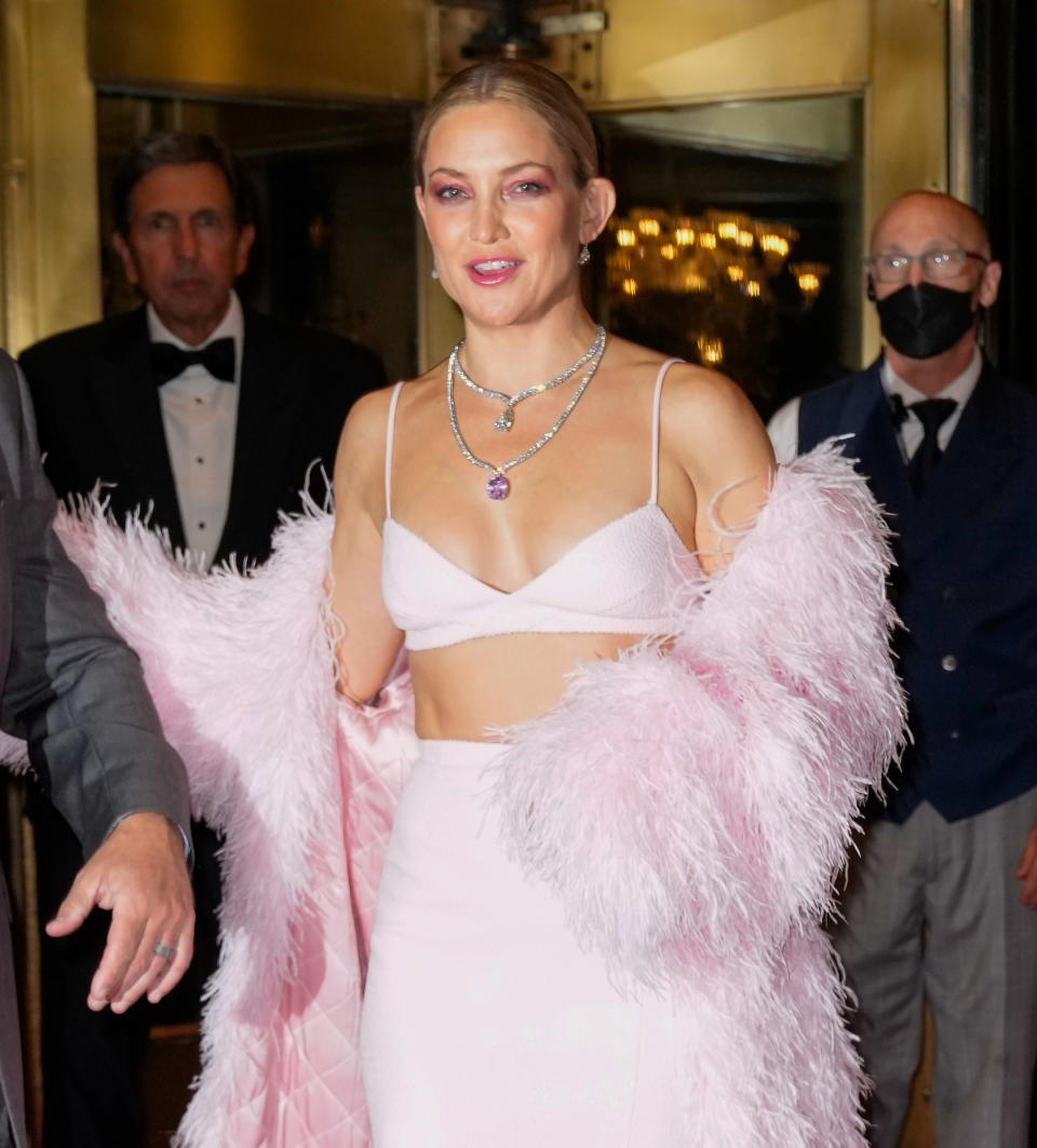 Kate walking at an event in a crop top, skirt, and matching feather jacket