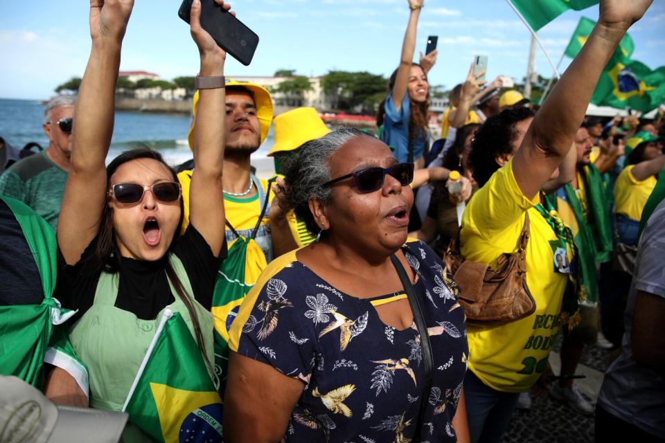 Supporters of Brazilian President Jair Bolsonaro raise arms and cheer