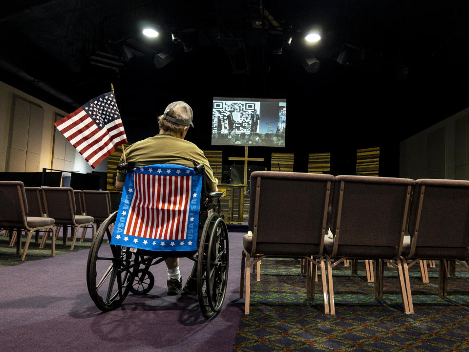 FILE - A man in a wheelchair watches a live video feed during the ReAwaken America Tour from inside the Cornerstone Church in Batavia, N.Y., Aug. 12, 2022. (AP Photo/Carolyn Kaster, File)