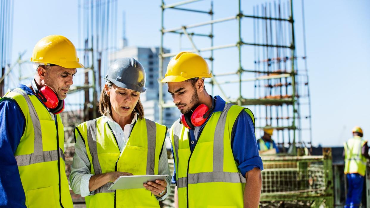 Male and female architects using digital tablet at construction site.