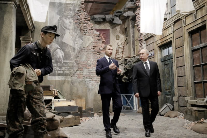 Russian President Vladimir Putin, right, examines an exhibition depicting a Berlin street after surrender in 1945 at 3D panorama 'Memory speaks. The road through the war' in St.Petersburg