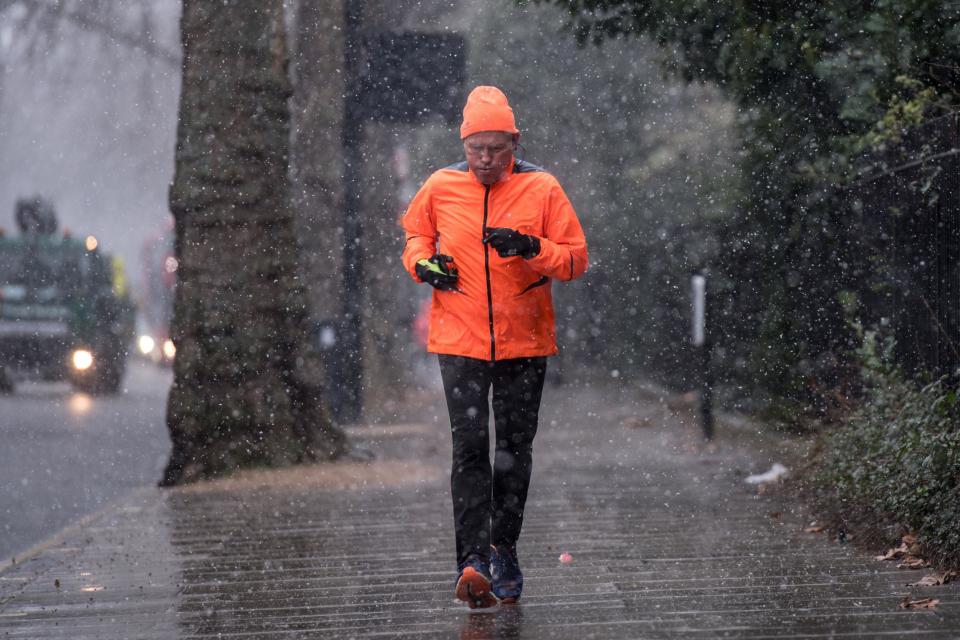 A man runs as snow falls in Kensington Gardens, Hyde Park, during the wintry conditions on Saturday (Getty Images)