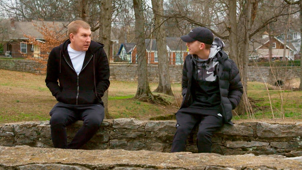 Todd Chrisley and Grayson Chrisley wearing black hoodies and sitting across from each other on Chrisley Knows Best