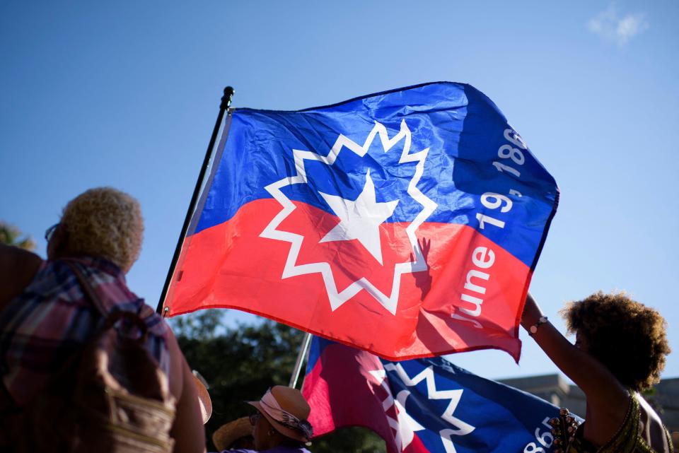 People carry a Juneteenth flag as they march during a Juneteenth re-enactment celebration in Galveston, Texas, on June 19, 2021. / Credit: MARK FELIX/AFP via Getty Images