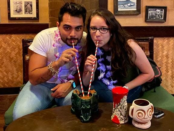 two people drinking out of a cocktail at trader sams bar at polynesian resort disney world