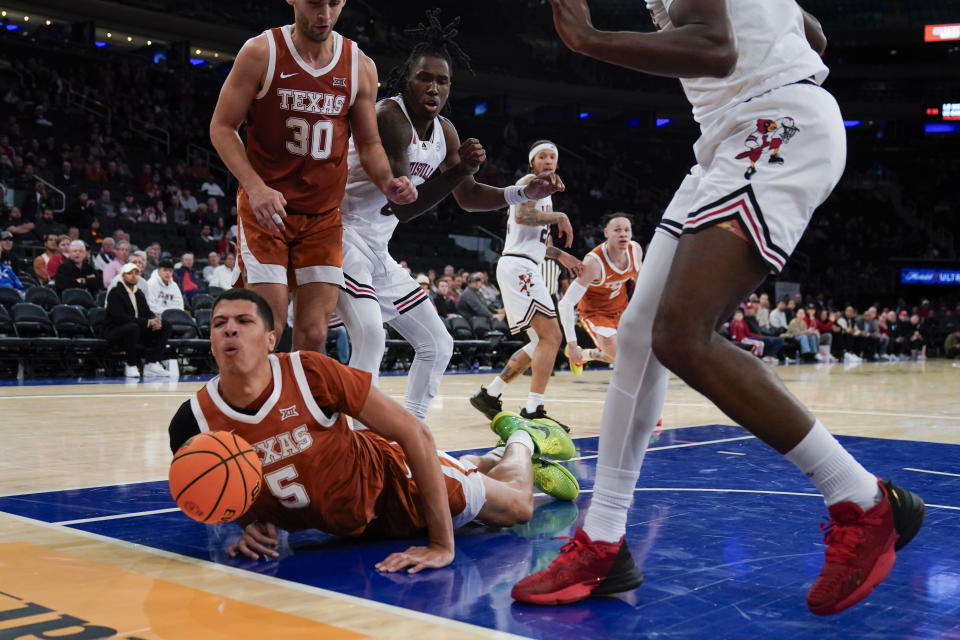 Texas's Kadin Shedrick, bottom, is fouled on his way to the basket during the second half of an NCAA college basketball game against Louisville, Sunday, Nov. 19, 2023, in New York. (AP Photo/Seth Wenig)