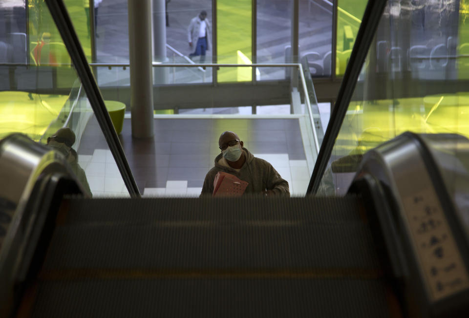 A masked man rides on an escalator in a mall in Johannesburg, Tuesday, July 14, 2020. The government has ruled it compulsory for people to wear face coverings in a bid to control the spread of COVID-19 as the country heads towards its coronavirus peak. (AP Photo Denis Farrell)