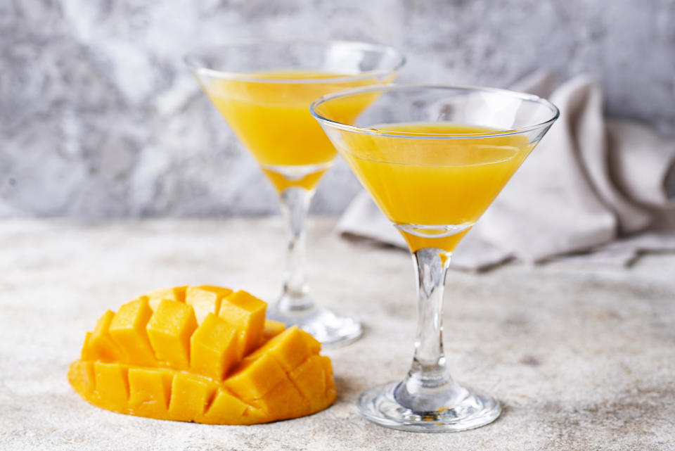 Zwei Mango Martini im Glas, daneben eine Mango in Würfeln