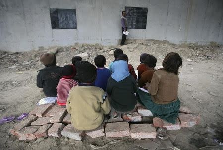 Children sit on bricks as they attend their class in an open charitable school built under a Delhi Metro Rail Corporation (DMRC) bridge in New Delhi February 4, 2012. REUTERS/Parivartan Sharma