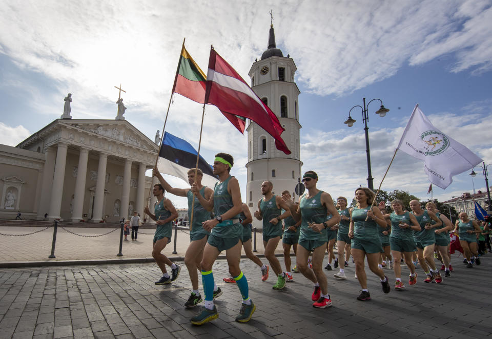 Lithuanian people take part in a traditional relay race Vilnius-Riga-Tallinn dedicated to the 30th anniversary of the Baltic Way at the Cathedral Square in Vilnius, Lithuania, Friday Aug. 23, 2019. Estonia’s prime minister says one should never forget the 1989 “Baltic Way” in which nearly 2 million people of then-Soviet Lithuania, Latvia and Estonia formed a human chain more than 600 kilometers (370 miles) long to protest Soviet occupation. (AP Photo/Mindaugas Kulbis)