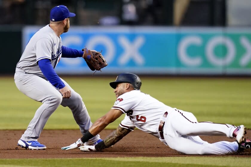 Arizona Diamondbacks' David Peralta (6) dives into second base with a double as Los Angeles Dodgers third baseman Max Muncy covers second base as he waits for a late throw during the first inning of a baseball game Tuesday, April 26, 2022, in Phoenix. (AP Photo/Ross D. Franklin)