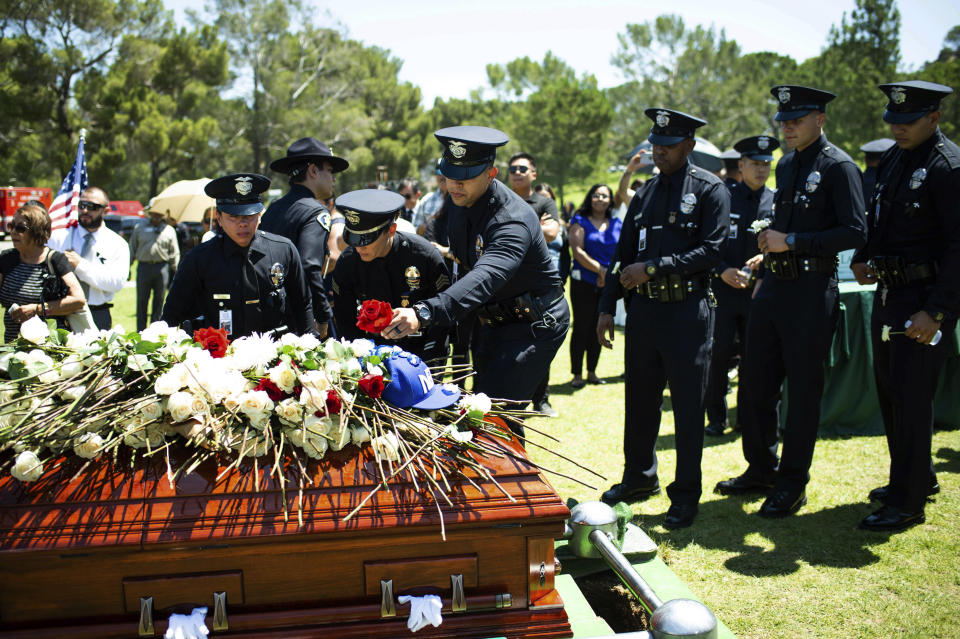 Los Angeles Police Department officers place flowers on fellow Officer Juan Jose Diaz's coffin during his funeral at Forest Lawn Hollywood Hills cemetery, Monday, Aug. 12, 2019, in Los Angeles. Diaz was killed while off duty in Lincoln Heights after visiting a taco stand. (Sarah Reingewirtz/The Orange County Register via AP)