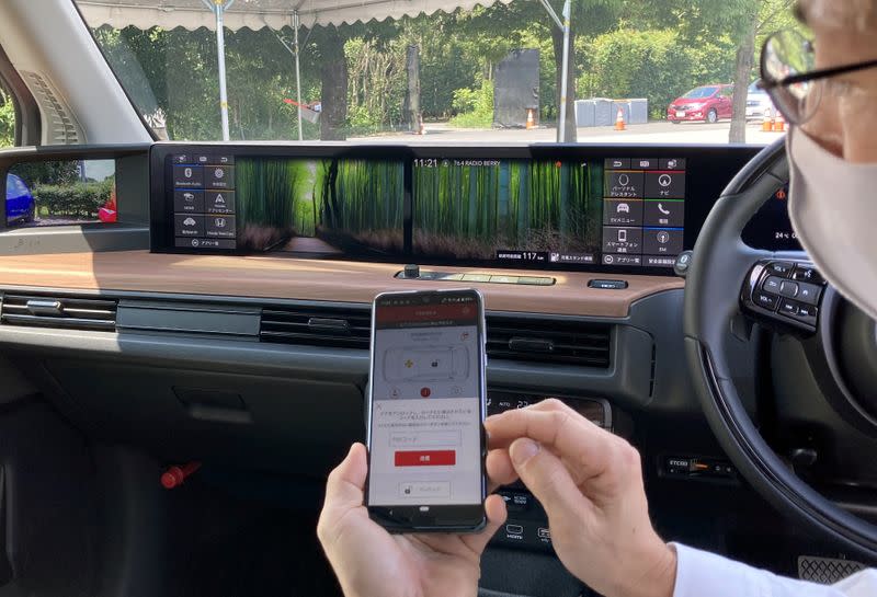 An employee of Honda Motor demonstrates a digital key app on a smartphone inside a Honda E electric car in Haga Town