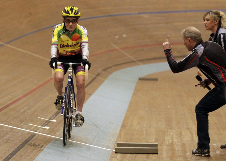 Trainer Robert Mistler (C) boosts cyclist Robert Marchand of France (L) next to trainer Magali Humbert-Perret during his attempt to set a world record for cycling non-stop for one hour, in the over 100- year old category, at the Union Cycliste Internationale (UCI) velodrome in Aigle February 17, 2012. Marchand, born November 26, 1911, cycled 24.251 km (15 miles) around the 200 metre indoor track to set the record on Friday. REUTERS/Denis Balibouse